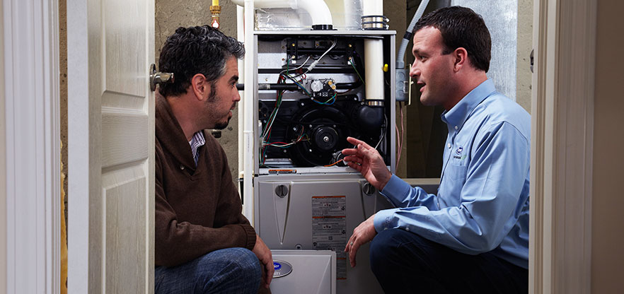 Carrier technician discussing furnace maintenance with homeowner